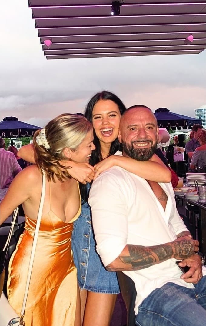 Three friends laughing and embracing together on a rooftop
